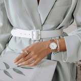Woman wearing watch and bracelet with white belt.