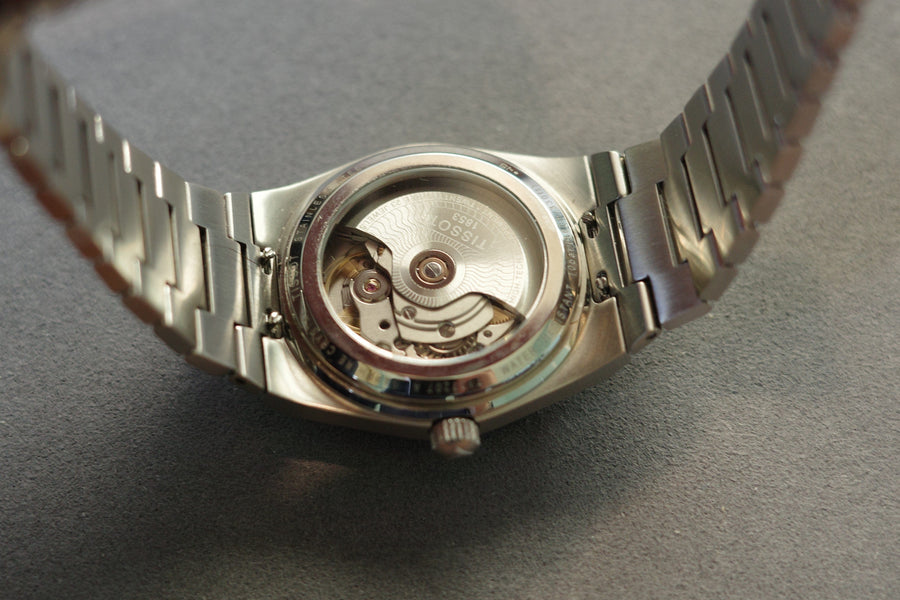 Back of a silver wristwatch showing the inner workings.