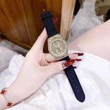 Guess women's watch with crystals, gold dial, black strap.