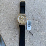 Guess women's watch with gold dial, crystals, and black rubber strap.