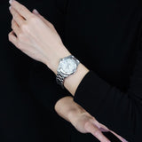 Woman's wrist wearing a silver watch, l_3d400ab5-7755-4191-a60f-033fa5dea0bd