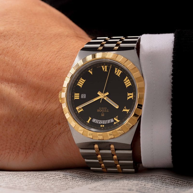 Tudor 2020 watch on wrist with gold accents.