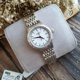 Tissot watch with silver band and white face on gray cushion